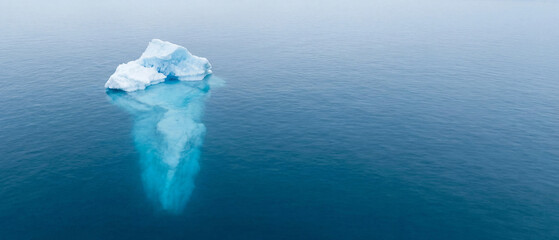 Small iceberg floating in open sea with turquoise underwater glow