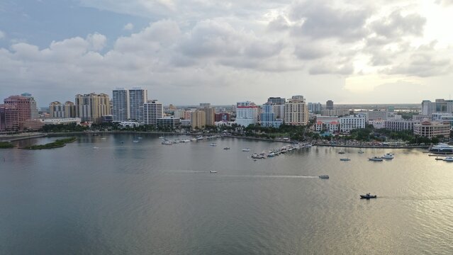 Aerial view of boats gently bobbing on the water near the cityscape under a cloudy sky, West Palm Beach, Florida, United States.