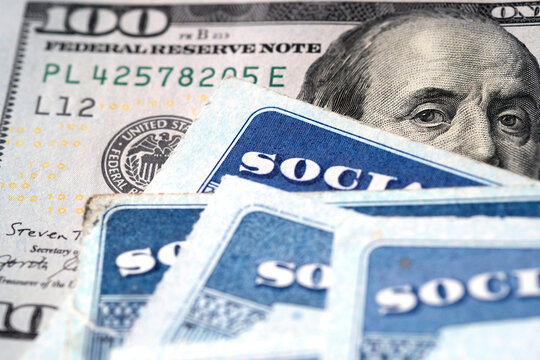 Social Security Cards with US One Hundred Dollar Bill $100 representing retirement and guarantee from the US government of old age benefits