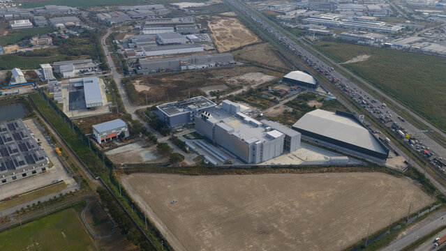 Aerial view of industrial buildings and warehouses alongside a busy highway, Chonburi, Thailand.