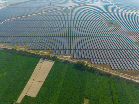 Aerial view of vast solar panel array contrasting with the vivid green fields, a testament to renewable energy integration, Gaibandha, Bangladesh.