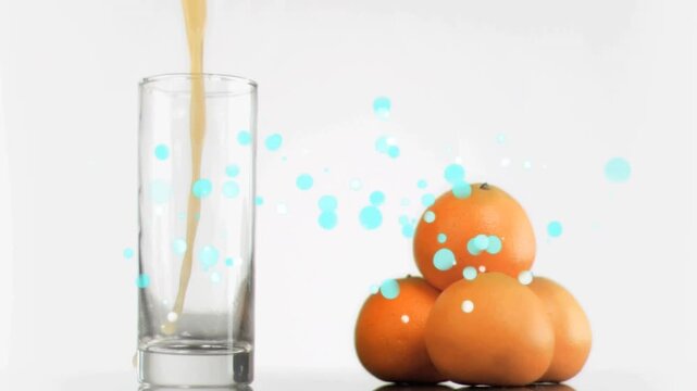 Tall clear glass and pyramid of oranges receiving pour from above showing filling, particle overlay