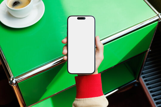 Hand Holding Smartphone with White Screen Green Table Mockup 