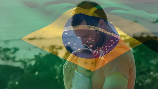 Hearing baby cooing, father holding, soothing family on rocky beach with moving Brazil flag overlay