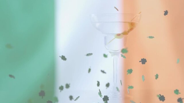 Gust sparking shamrocks swirling, falling over tricolor revealing goblet outline honoring Irish