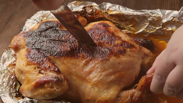 A woman's hands use a knife to cut a whole roast turkey