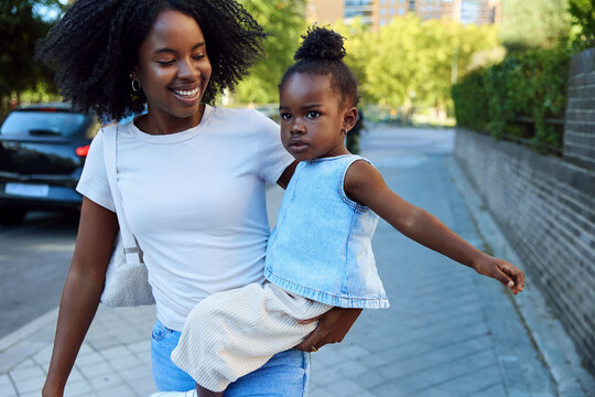 Smiling mother carrying daughter on the way to school