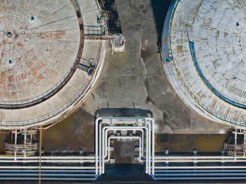 Aerial view of colossal, weathered tanks and intricate pipework create a stark industrial tableau under the diffused light, Kalochori, Thessaloniki, Greece.