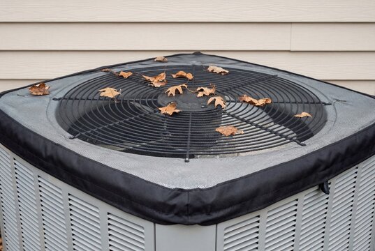 Air conditioning unit with a protective mesh cover and fallen leaves