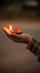 Woman's Hand Holding a Lit Diya Lamp During a Festival, Adorned with Colorful Bangles, Symbolizing Light and Hope