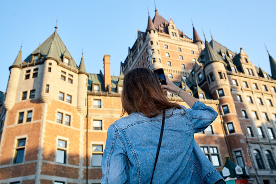 Woman with denim jacket taking a photo of Chateau Frontenac