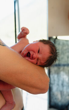 Crying newborn held on forearm