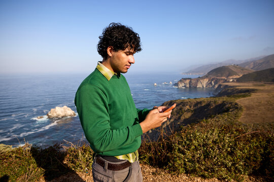 Man uses his phone on the ocean coast