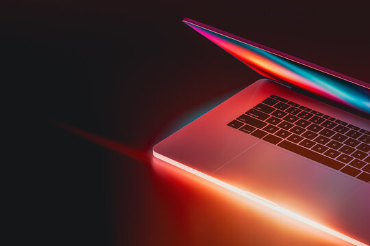 Laptop glows with vibrant neon lights in a dark setting