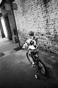 Child riding a bicycle along a brick wall