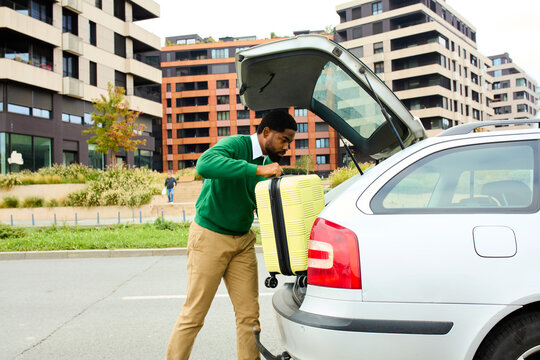 Man loads suitcase into vehicle