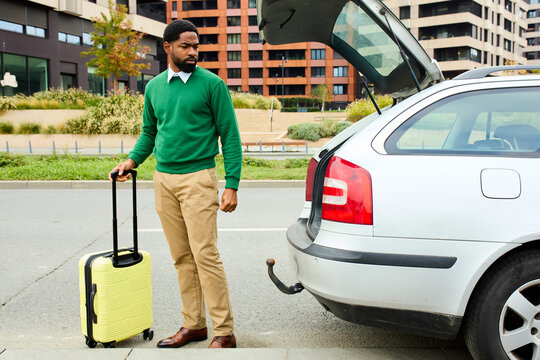 Man stands by the car with a suitcase