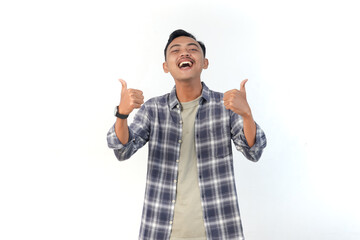 Naklejka premium Asian man wearing a plaid shirt with a joyful expression is giving thumbs up on an isolated white background.