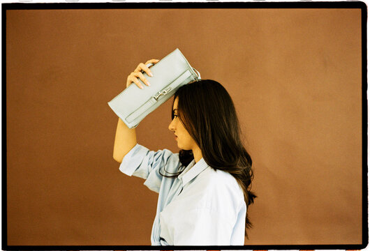 Woman holding blue handbag on head