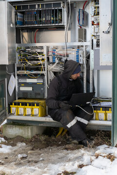 A technician using a laptop to maintain the connection system outdoors