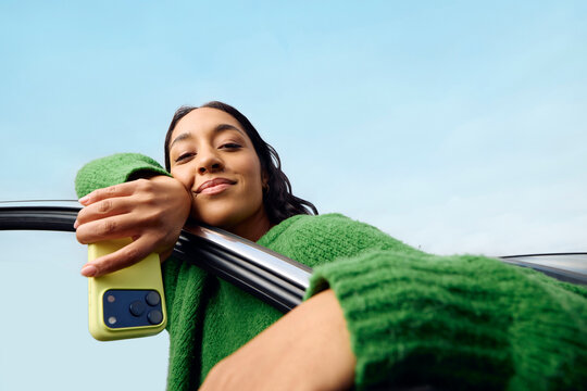 Casual woman leans on a car door
