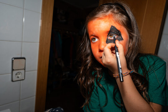 Child Applying Pumpkin Makeup for Halloween 