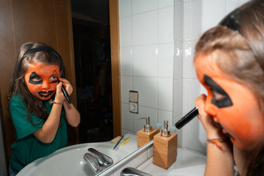 Child Applying Pumpkin Makeup for Halloween 