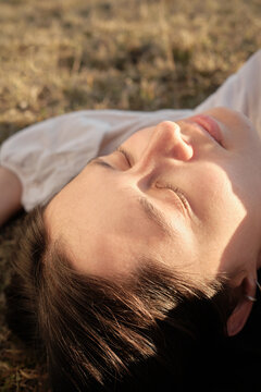 Woman relaxing in sun on grassy ground in peaceful outdoor setting