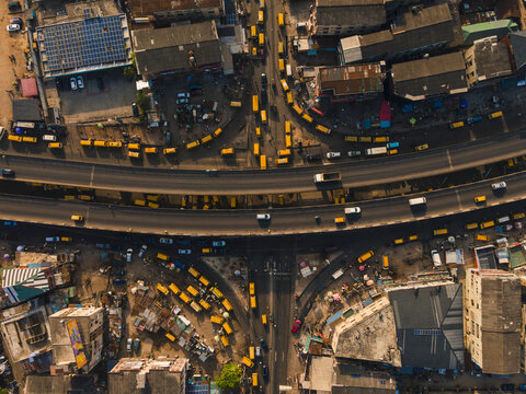 Aerial view of a bustling interchange teeming with bright yellow buses weaving through the roads and under the overpass, Ikeja, Lagos, Nigeria.