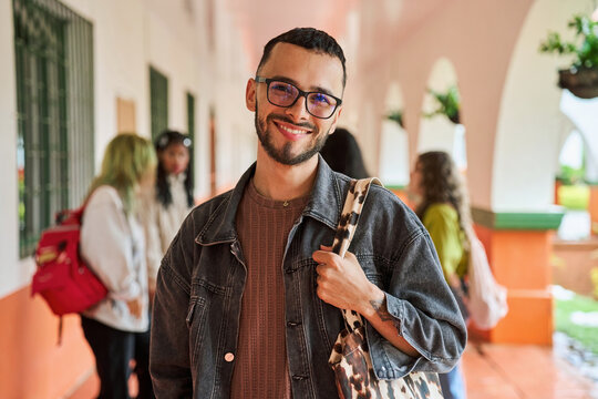 Young male student smiling at college campus hallway