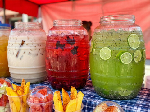 Row of traditional Mexican vitroleros with horchata, jamaica, and lime aguas frescas.