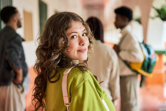 Female student smiling, looking back in university hallway