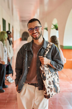 Happy student standing in university hallway smiling