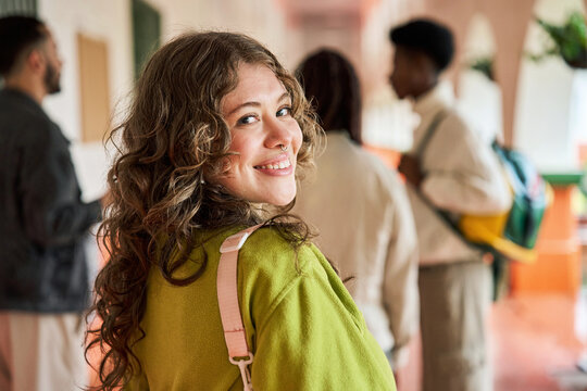 Female student smiling looking back at campus hallway