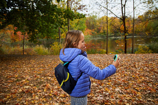 Young girl taking a selfie with a digital camera, fall scene