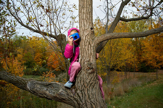 Child in a tree taking a photo