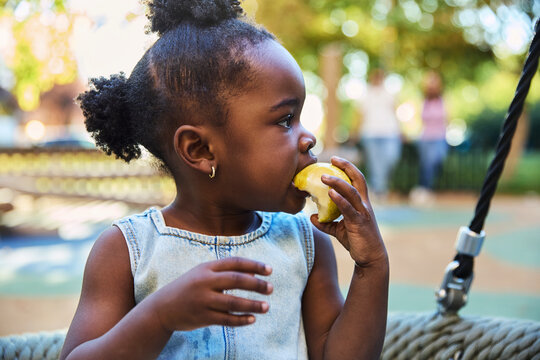 Girl eating a pear at the playground