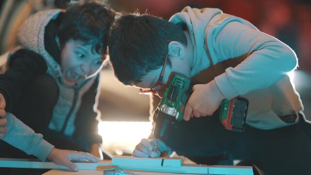 Young boys learning woodworking with electric drill