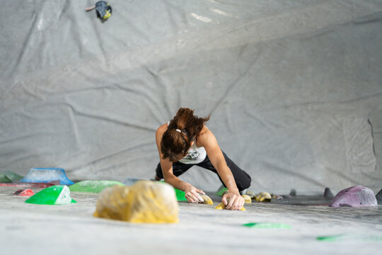Woman bouldering indoors, gaining strength and concentration