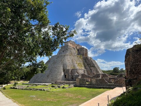 Mid far view of Mayan pyramid, "Piramide de Uxmal" (Pyramid of Uxmal), green grass, sunny day, blue skies, white clouds, Uxmal, Yucatan, Mexico