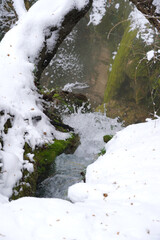 A small picturesque waterfall located in a mountainous forest area during the cold season nature water winter snow flora