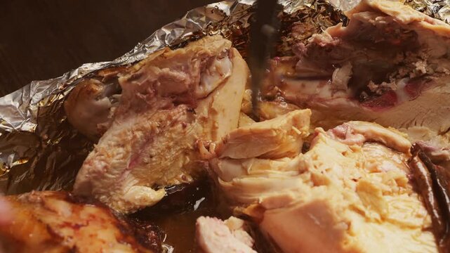 A woman's hands use a knife to cut a whole chicken baked with a spice crust on foil