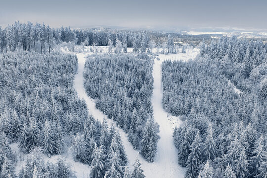 Aerial view of snow-laden trees and ski slopes create a striking contrast against the stark white landscape, a winter wonderland scene., Winterberg, North Rhine-Westphalia, Germany.