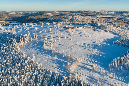 Aerial view of a snow-blanketed landscape with scattered trees and distant hills, creating a serene winter scene, Winterberg, North Rhine-Westphalia, Germany.