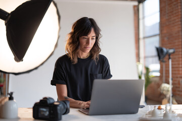 Obraz premium Professional content creator reviews product arrangement on screen, professional female blogger checks shoot setup with precision, professional workspace includes camera gear and softbox lighting