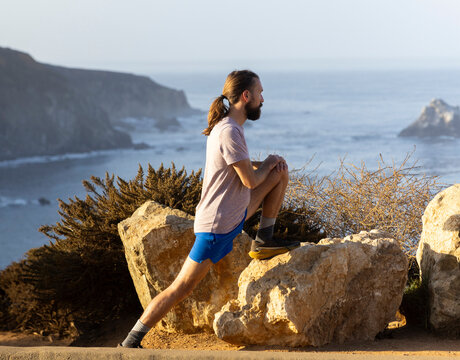 Athlete stretch before run Big Sur ocean landscape 