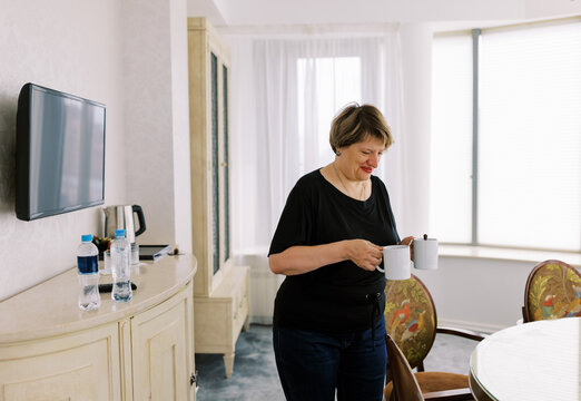 Woman Carrying Cups of Coffee in a Bright Hotel Room