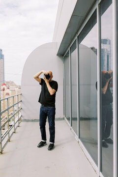 Man Taking Pictures on Rooftop Balcony With City View