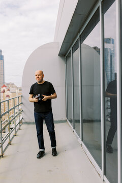 Man With Camera on Balcony in Urban Setting Capturing City Views