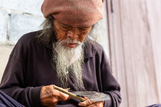 Senior Thai villager carving bamboo at rural home